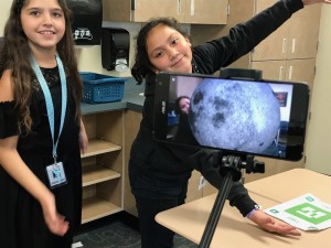 girl demonstrates how the moon appears on her desk